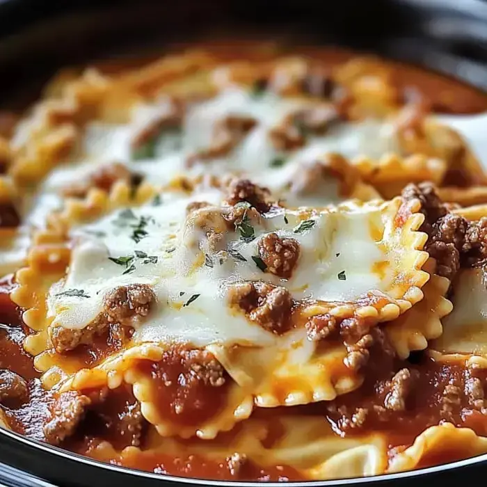 A close-up of layered pasta with meat sauce and melted cheese, garnished with herbs.