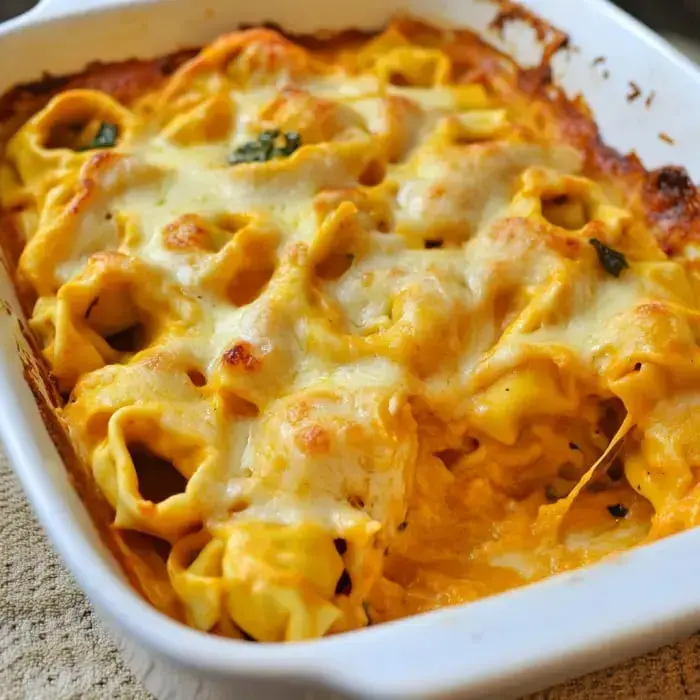 Warm baked tortellini dish covered with herbs, melted cheese, and creamy sauce.
