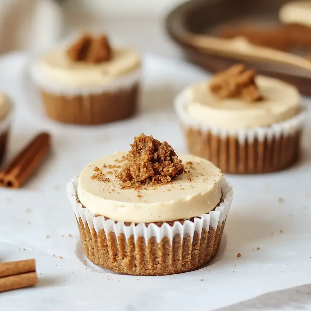 A close-up of several cinnamon-flavored cupcakes topped with a creamy frosting and sprinkled with brown sugar.